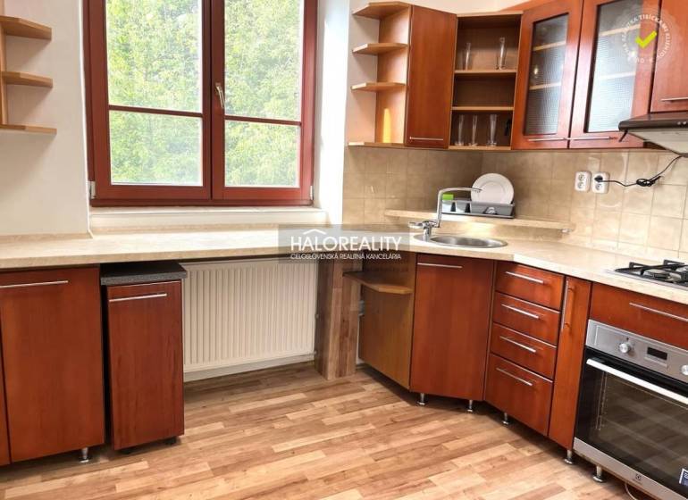 A kitchen in a 3-room apartment with a wooden cabinet, a window overlooking greenery.