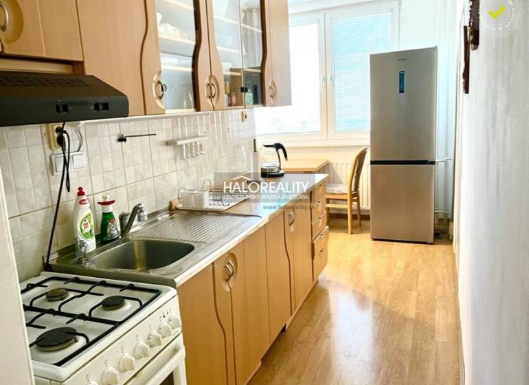 A kitchen with a gas stove and a refrigerator in a 3-room apartment, light-colored countertop.