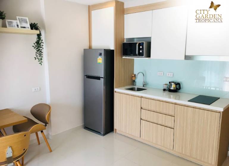 Kitchen corner in a 2-room apartment with a refrigerator, microwave, and wooden furniture.