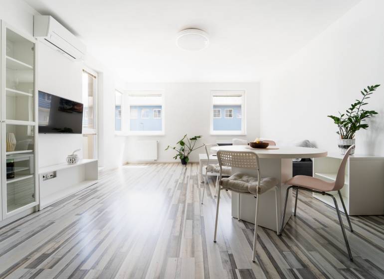A bright living space with large windows and a dining table in a 2-room apartment.