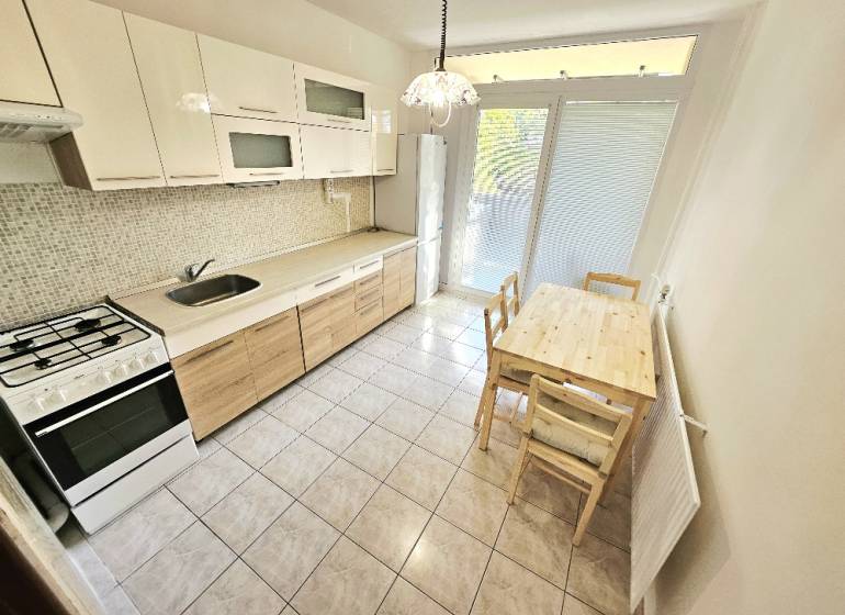Kitchen in a 3-room apartment with a dining table, gas stove, and refrigerator.