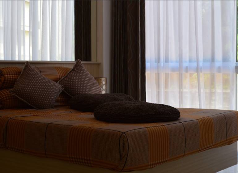 A bed with brown bedding and pillows in a 2-room apartment.