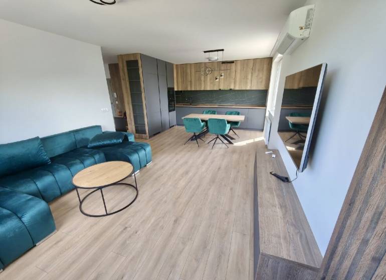 Living room and kitchen in a 3-room apartment with a turquoise sofa and a dining area.