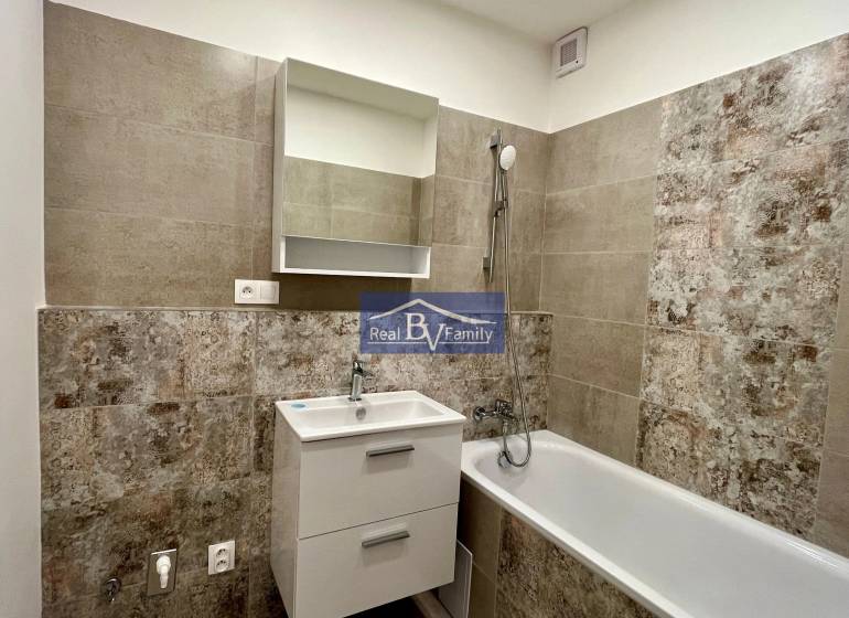 A bathroom with a bathtub, a sink, and tiles in a two-room apartment.