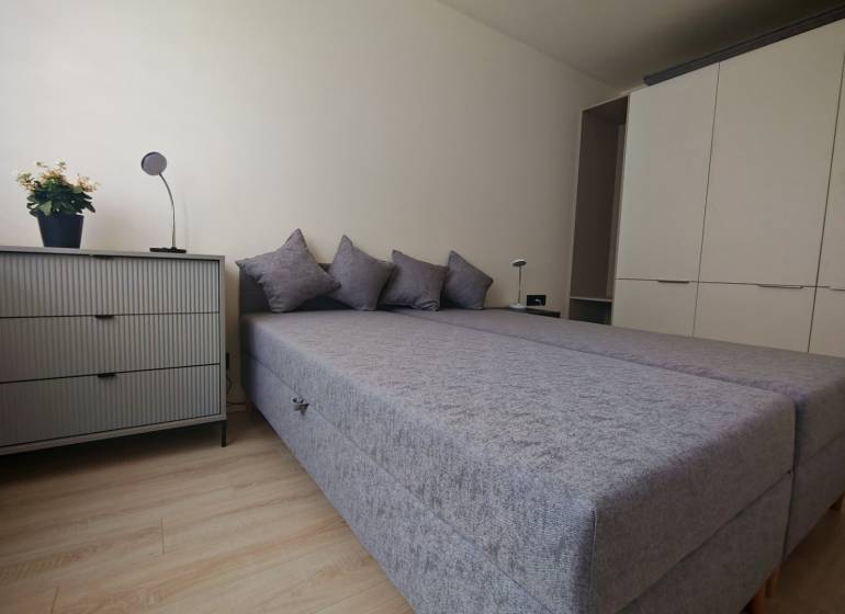 A bedroom with a bed, wardrobe, and dresser in a studio apartment.