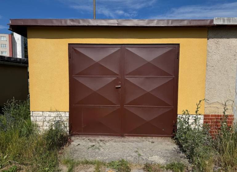 Brown garage on Záhradná Street in Svit with plants around.