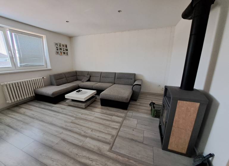 Living room with a corner sofa, fireplace stove, and a table in a family house.