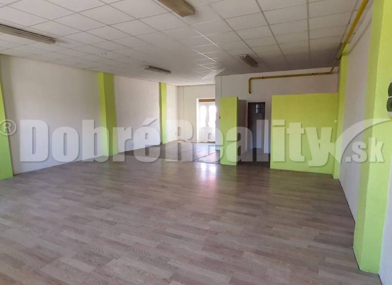Spacious commercial spaces with laminate flooring and white walls with green stripes.
