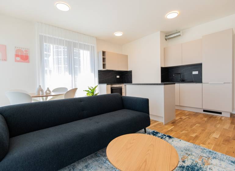 Living room and kitchen in a 3-room apartment with a sofa, coffee table, and dining table.