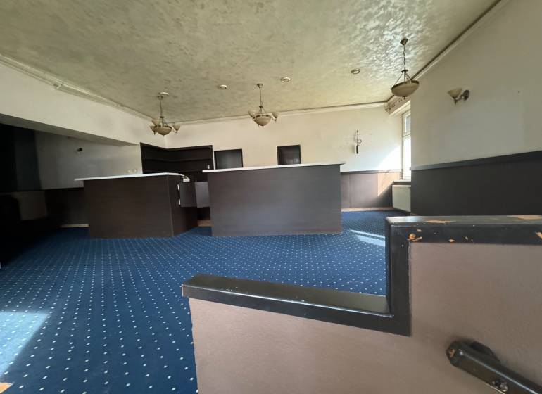 Interior of commercial spaces with carpets and a counter, illuminated by pendant lamps.