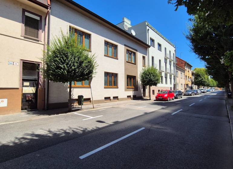 A street in Piešťany with apartment buildings and parked cars.