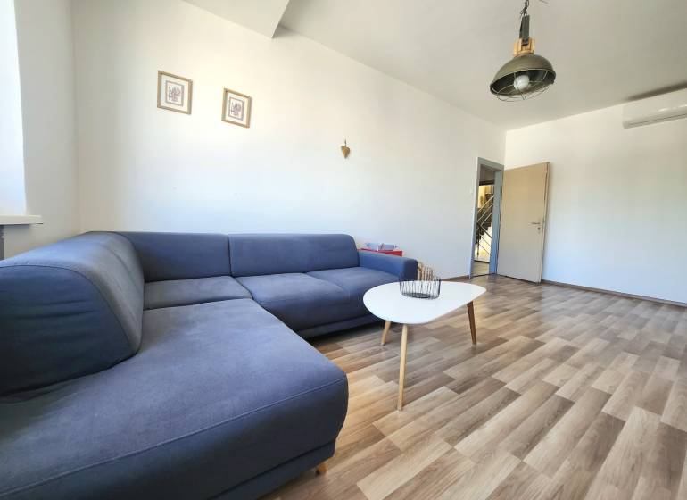 Living room with a blue sofa, table, and wooden floor in a 2-room apartment.