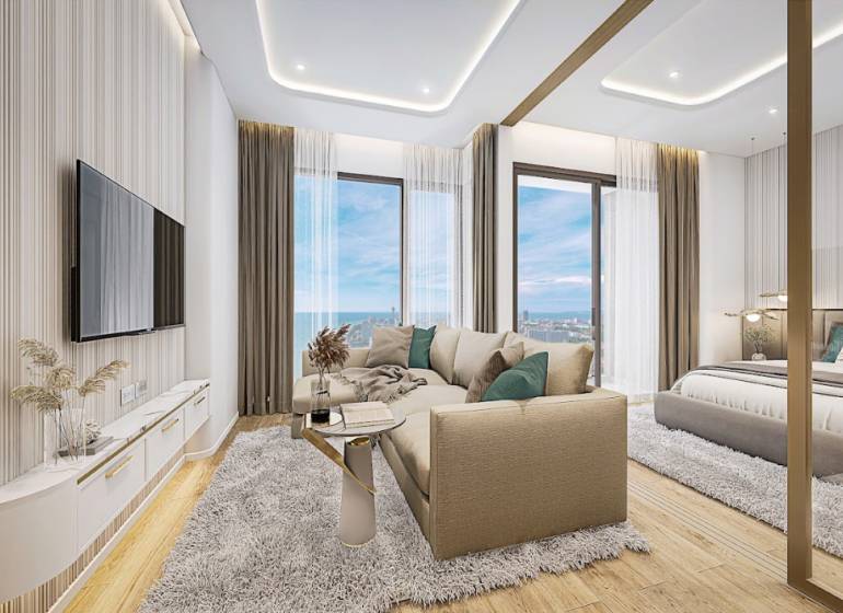 Living room of a 2-room apartment with a sea view, featuring a comfortable couch and a television.
