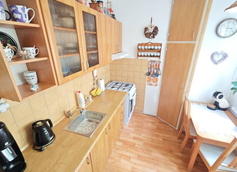 A kitchen in a 2-room apartment with wooden furniture, a dining corner, and decorations.
