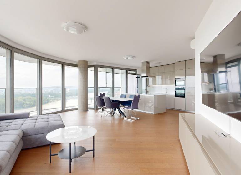 Bright living room in a 4-room apartment with large windows and a modern kitchen.