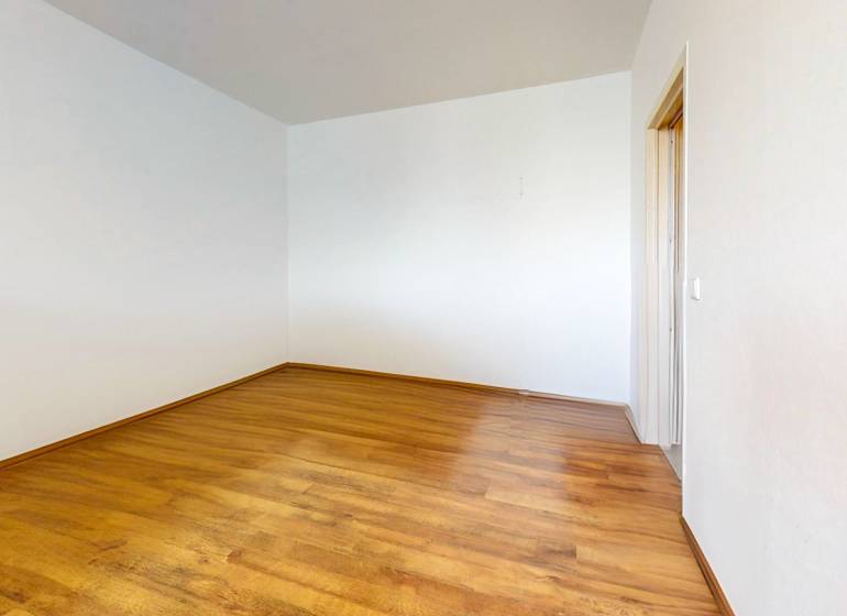 Empty room with wooden flooring in a studio apartment. White walls, simple design.