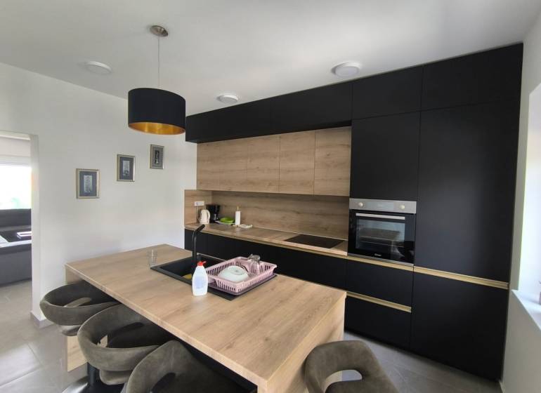 The kitchen in a 4-room apartment with dark cabinets and wooden details.