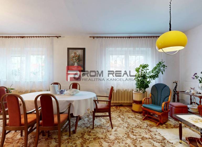 Living room in a family house with a table, chairs, decorations, and a yellow lamp on the ceiling.