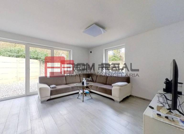 Living room in a family house with a sofa, windows, and a television.
