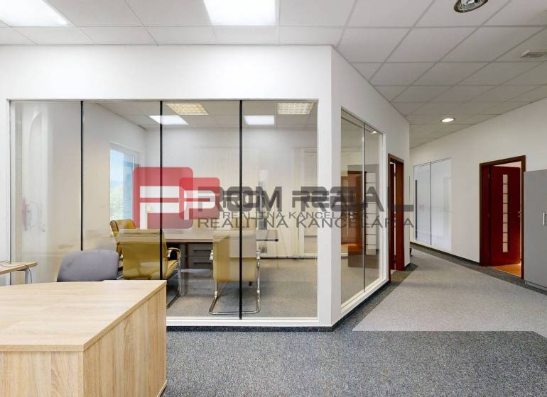 Offices with glass partitions, a wooden desk, and gray office chairs.