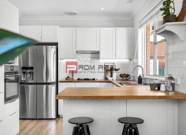 A kitchen in a 3-room apartment with a wooden countertop and a stainless steel refrigerator.