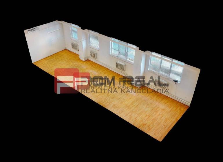 Interior of a warehouse and hall with wooden flooring and large windows.