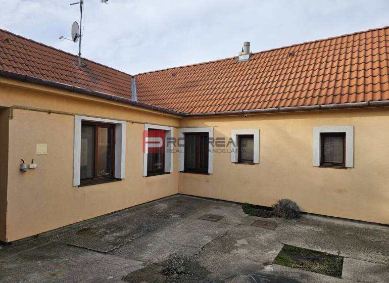 The yard of a family house on Slnečná Street in Pezinok with concrete paving and an orange facade.