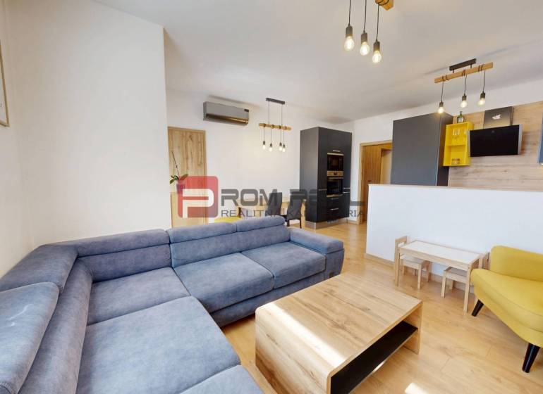 Living room of a three-room apartment with a blue sofa, wooden furniture, and a yellow armchair.