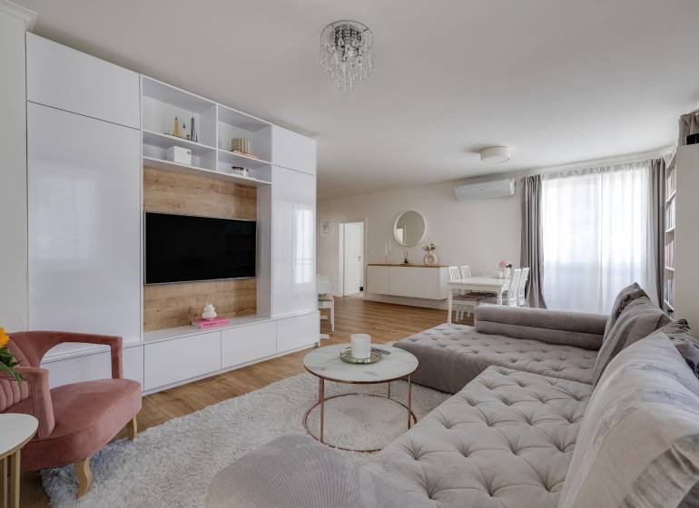 Living room in a 3-room apartment with a comfortable sofa, TV wall, and dining table.