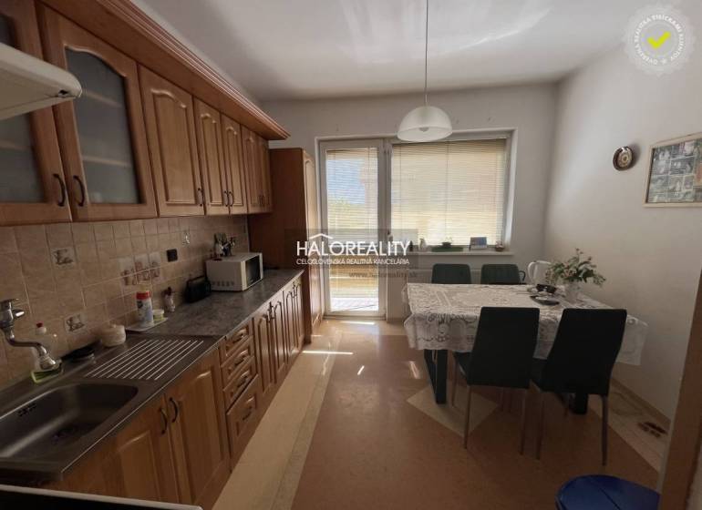 A kitchen in a 3-room apartment with a dining table, cabinets, and balcony doors.