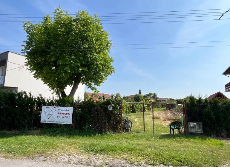 Plots - housing in the village of Dolný Bar, fenced plot with a tree and a gate.