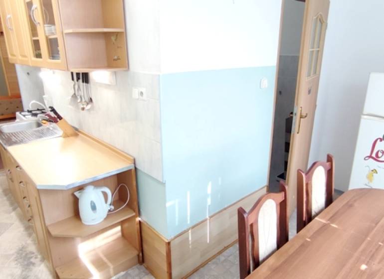 A kitchen connected to a dining table in a 2-room apartment, equipped with basic appliances.