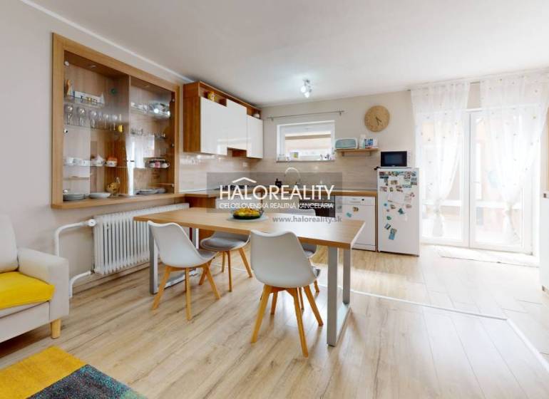 Interior of a family house with a dining table, kitchen, and shelves for dishes.