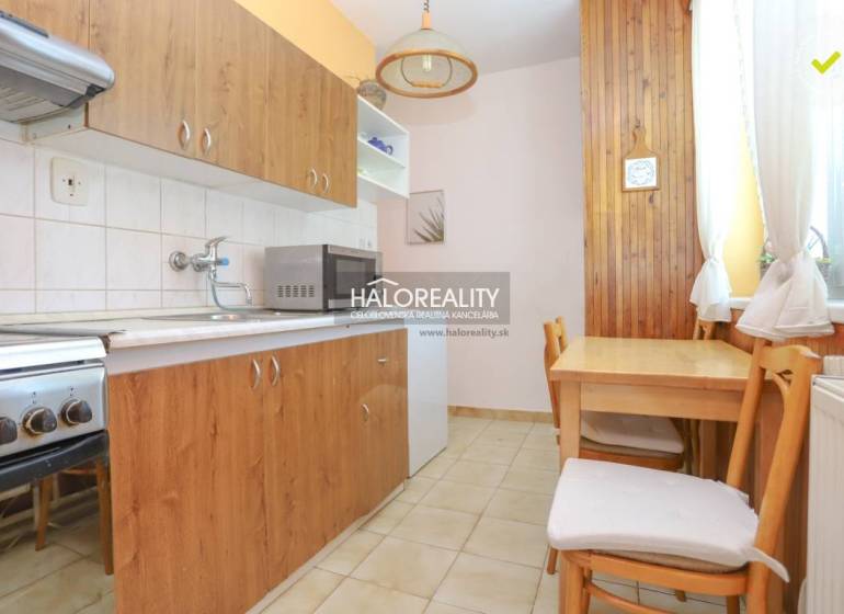 A kitchen in a 3-room apartment with wooden furniture, a stove, and a microwave oven.