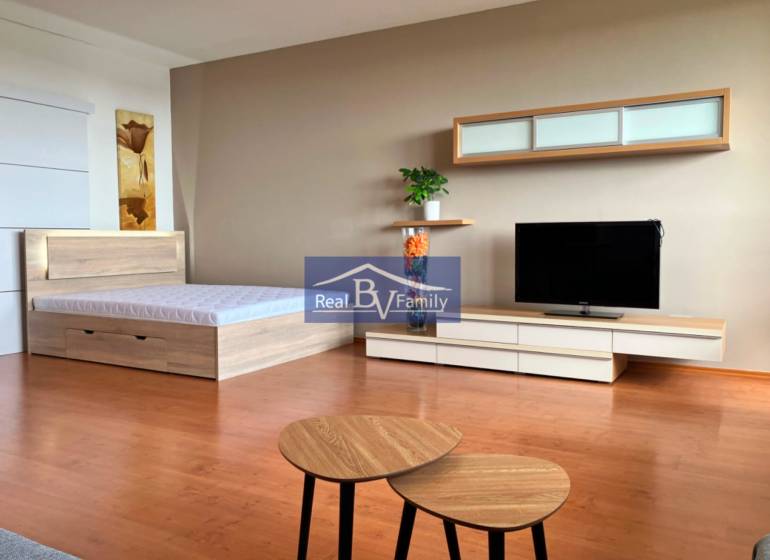 A studio apartment with a bed, TV, furniture, and wall decorations.