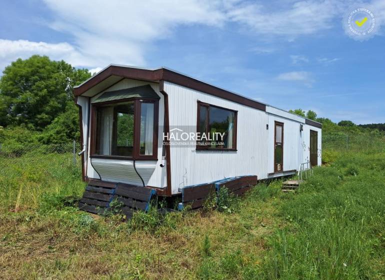 A mobile cottage in Boleráz surrounded by grass and trees in the background.