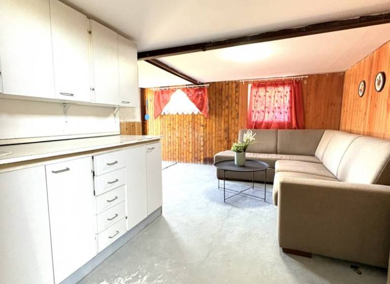 The interior of a cottage with a white kitchen unit and a comfortable sofa.