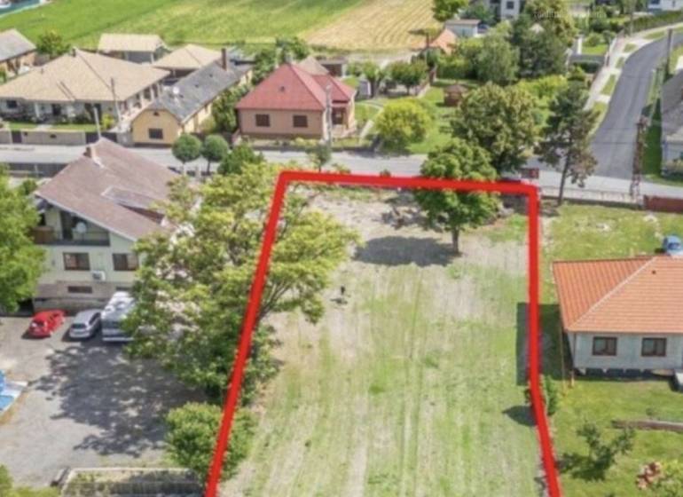 A residential plot in Čiližská Radvaň, surrounded by houses and greenery, offers beautiful views.
