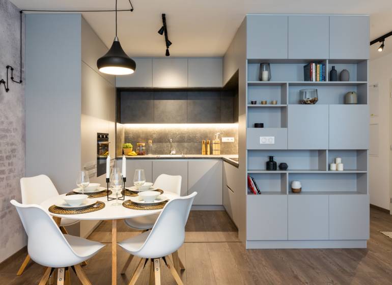 Dining room in a 2-room apartment with a modern table and chairs, gray kitchen cabinets.