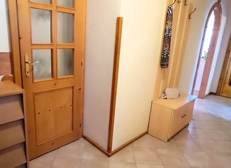 A hallway in a 3-room apartment with wooden furniture and decoration in a vase.