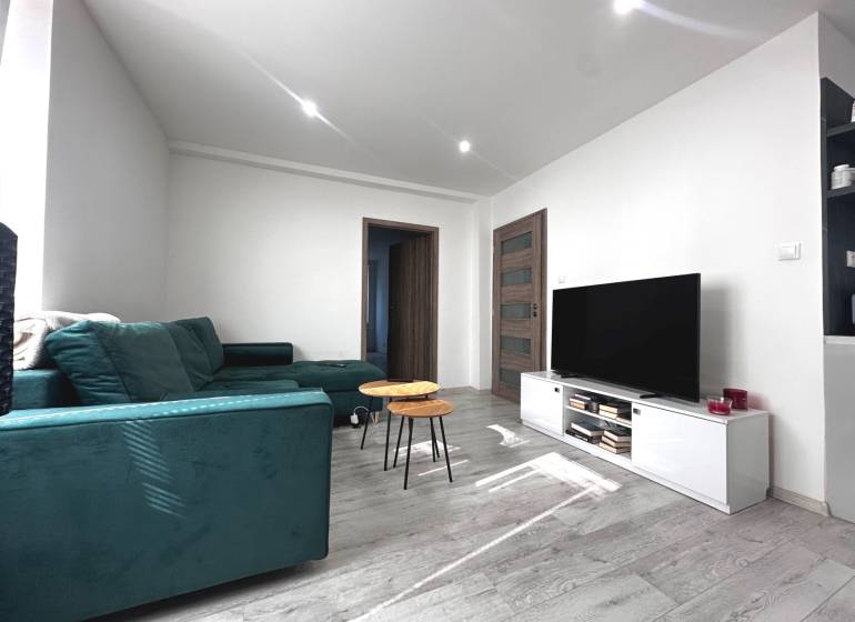 Living room in a 2-room apartment with a sofa, TV, table, and minimalist interior.