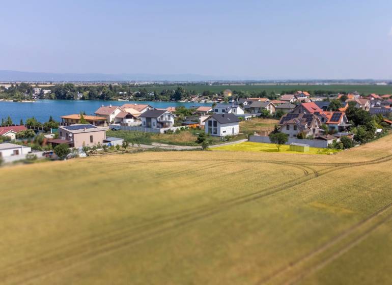 Plots - housing in Dunajská Lužná with a view of the lake, houses, and fields.