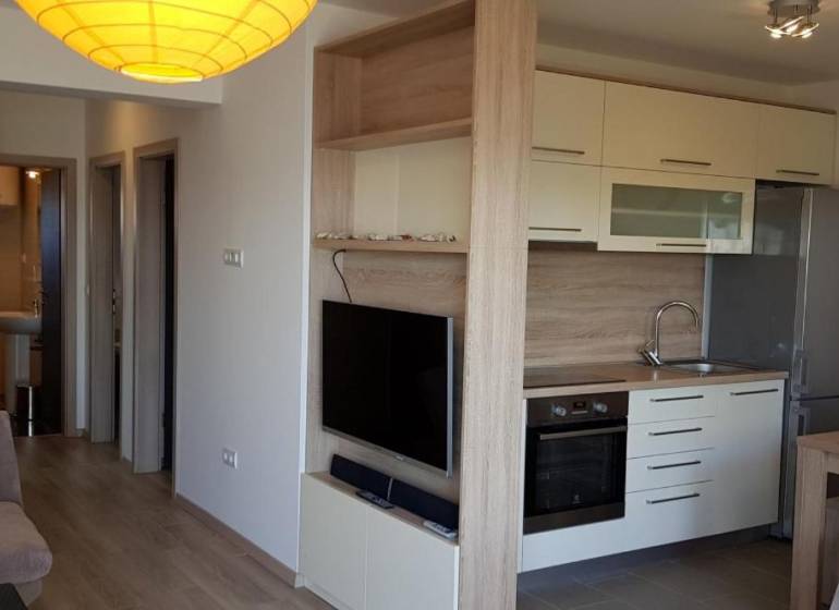 A kitchen in a 3-room apartment with built-in appliances and a TV on the wall.