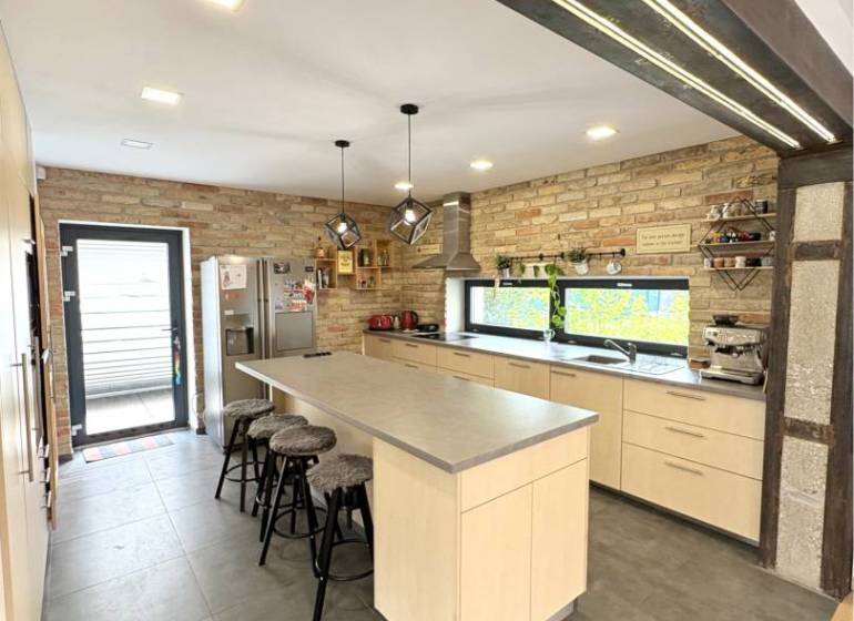 A kitchen with a brick wall and an island in a family house.
