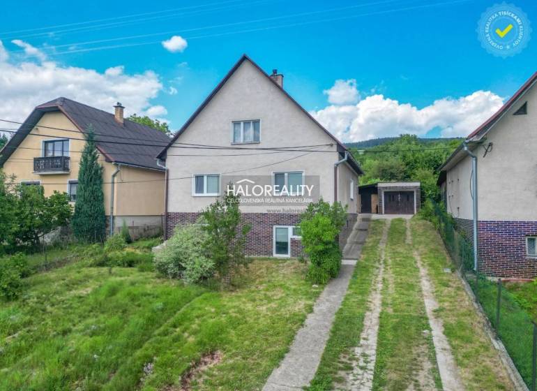 A family house in Dolná Mariková, with an access road and surrounding greenery under a blue sky.