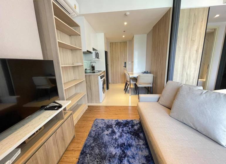 Living room in a two-room apartment with a sofa, television, and dining area.