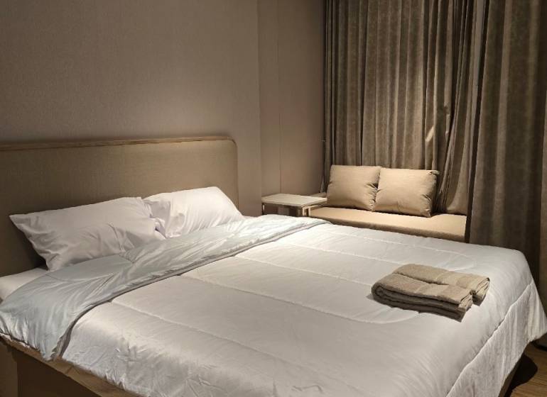 Bedroom in a one-room apartment with a double bed and a brown carpet.