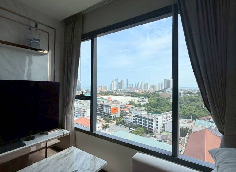 Living room of a 3-room apartment with a view of the city, a comfortable couch, and a TV stand.