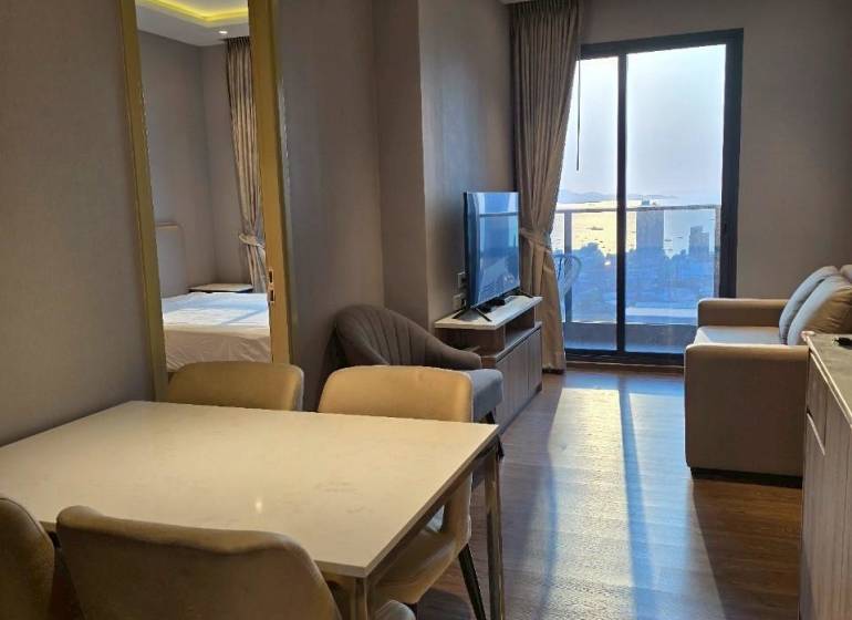 Dining area in a 3-room apartment with a view of the living room and balcony.