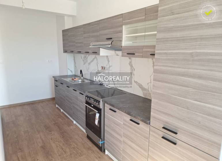 A kitchen in a 2-room apartment with wooden flooring and gray cabinets.